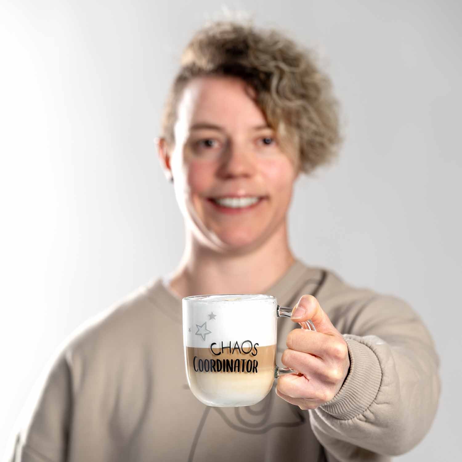 Person hält Glastasse UFFICIO mit Schriftzug CHAOS COORDINATOR
