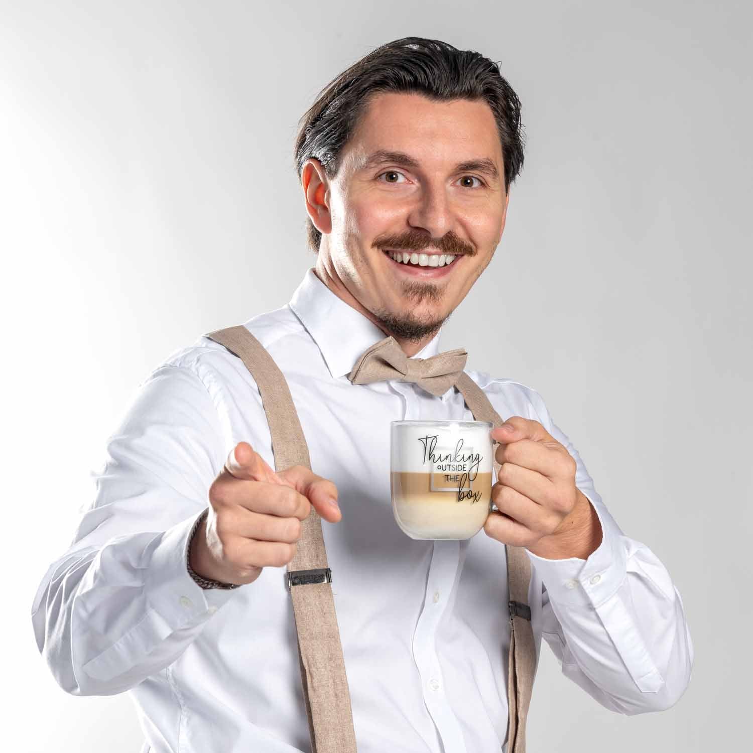 Mann hält Glastasse UFFICIO mit Gravur 'Thinking outside the box