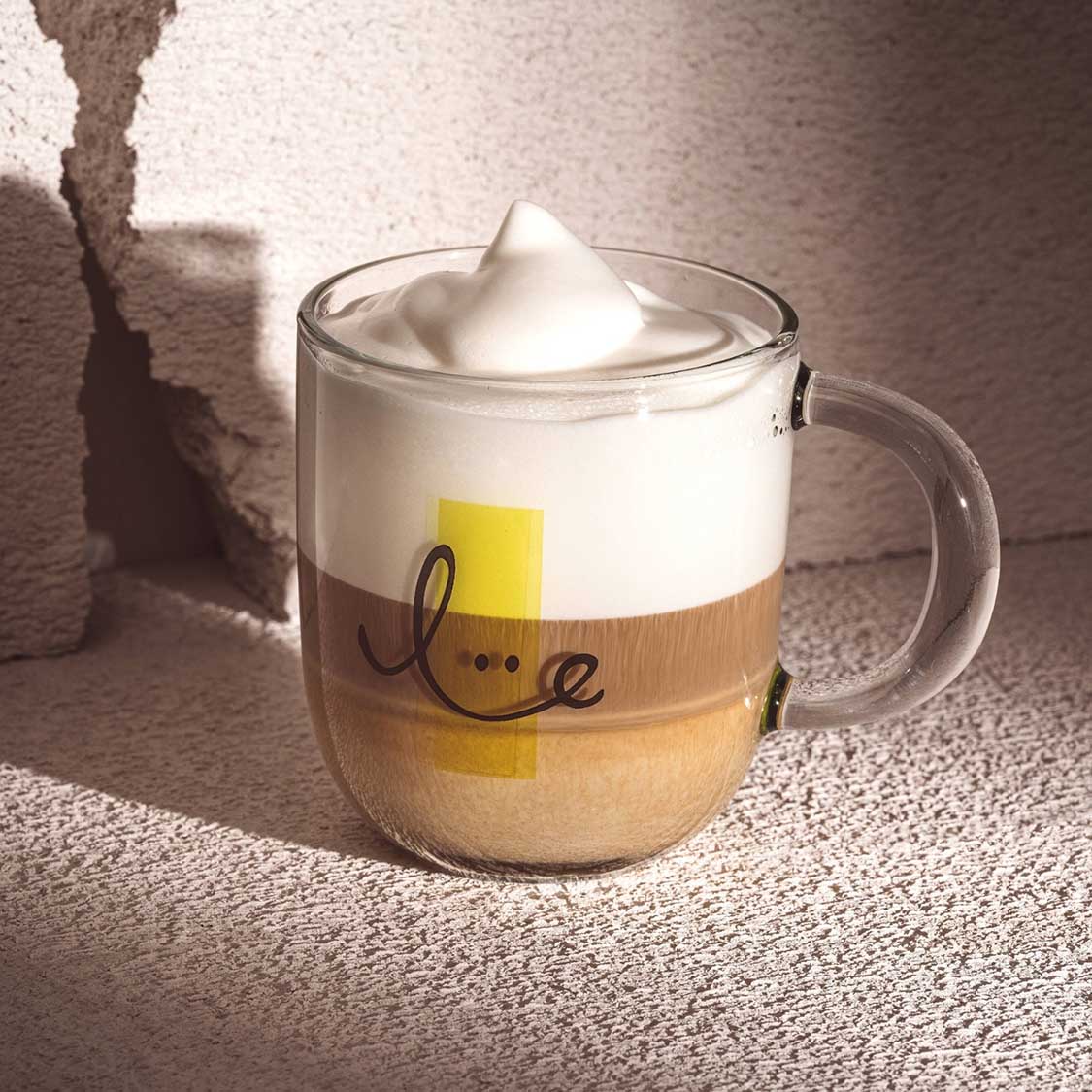 Tasse EMOZIONE mit Kaffee, Milchschaum und "smile" Schriftzug auf Schreibtisch