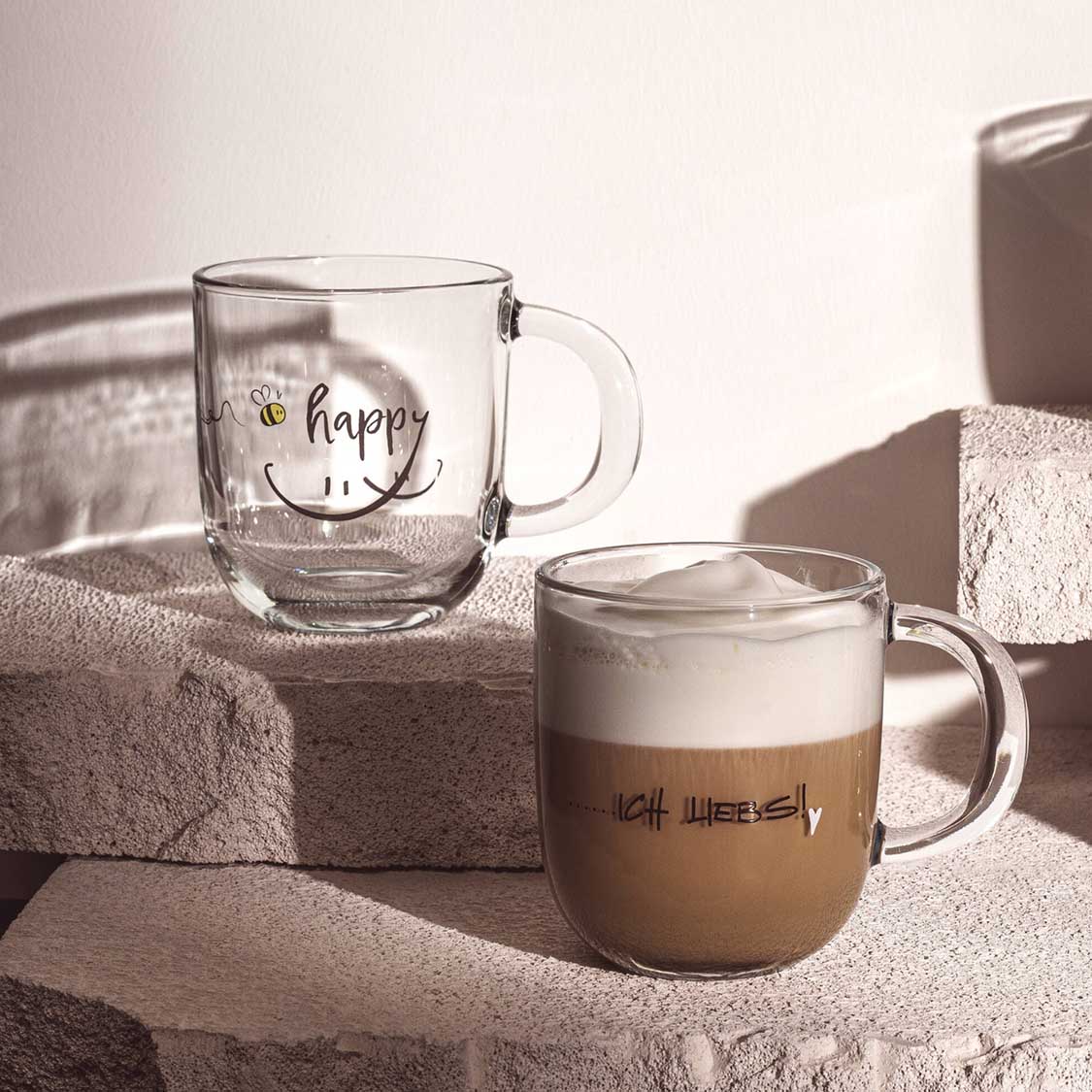 Tasse EMOZIONE 'happy' mit Gravur, eine gefüllt mit Kaffee auf Dekoelementen