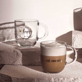Tasse EMOZIONE 'happy' mit Gravur, eine gefüllt mit Kaffee auf Dekoelementen