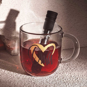 Tasse EMOZIONE mit rotem Heißgetränk, Zitronenschale und Weinflasche, Sonnenlicht und Schatten