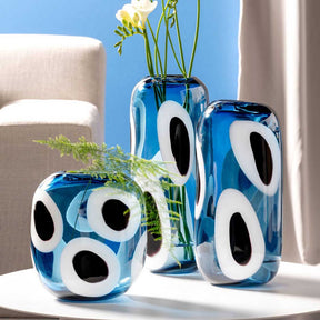 Vase OCCHI BLU in Blau mit weißen Augen-Motiven, gefüllt mit gelben Blüten und Grün
