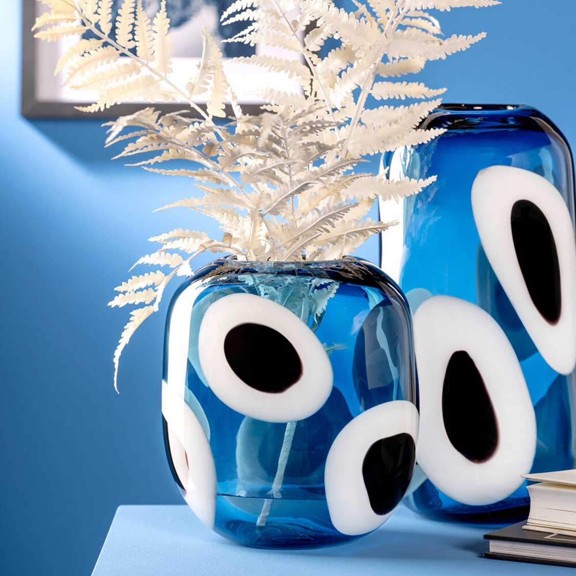 Blaue Glasvase OCCHI BLU mit weißen Augen-Motiven, gefüllt mit weißem Trockenblumenstrauß