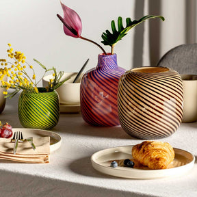 Vase FILO COLORI pink mit Blumen auf gedecktem Tisch neben Croissant