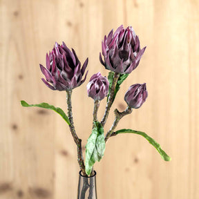 Lila Artischocke FIORE in Glasvase vor hellem Holzhintergrund