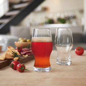 Bierglas TAVERNA 330 ml mit Bier gefüllt, leeres Glas daneben, Tisch mit Snacks und roten Paprikas
