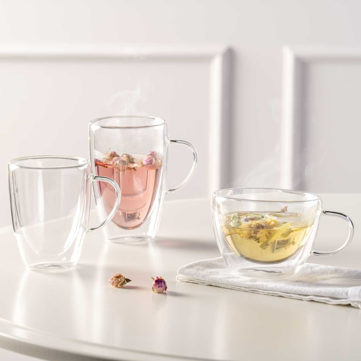 Doppelwandtassen DUO mit Tee und Kräutertee auf weißem Tisch