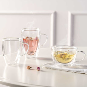 Doppelwandtassen DUO mit Tee und Kräuteraufguss auf weißem Tisch