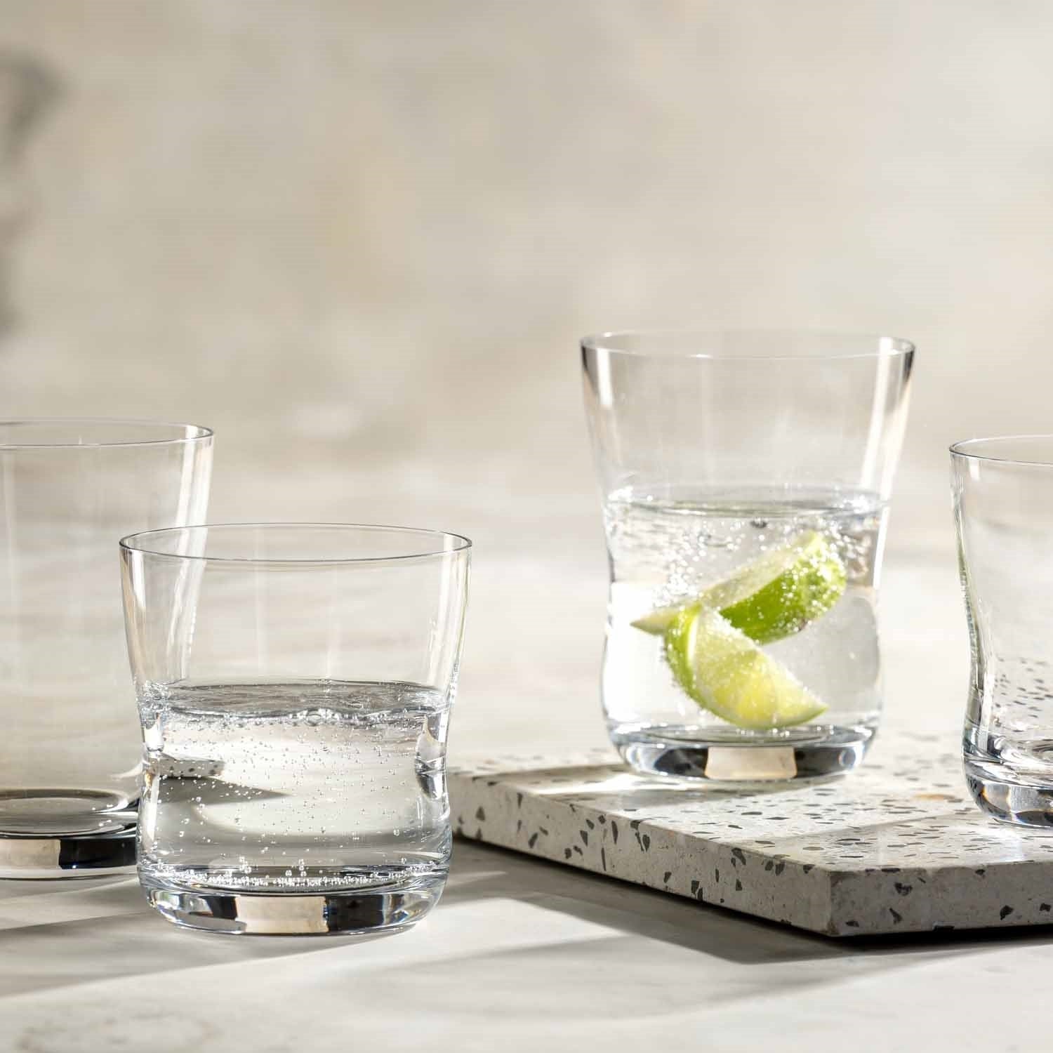 Trinkgläser VITA auf Betonplatte mit Wasser und Limettenscheibe