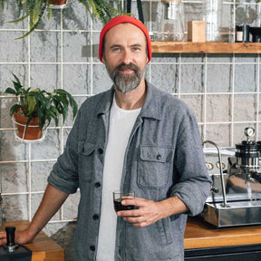 Mann mit Espressoglas in Werkstatt-Umgebung