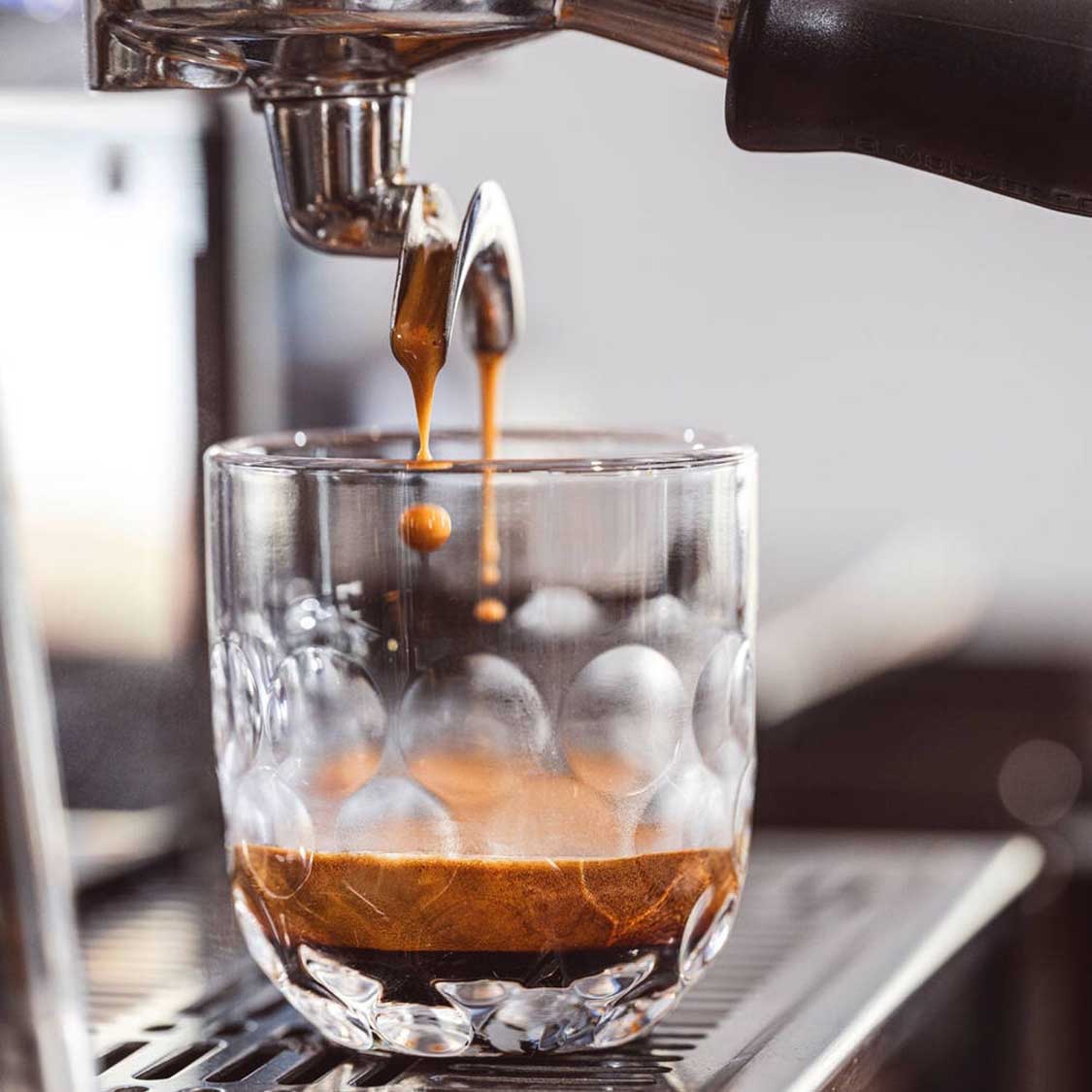 Kaffeeglas GOCCE wird mit Espresso gefüllt, Eiswürfel im Glas sichtbar