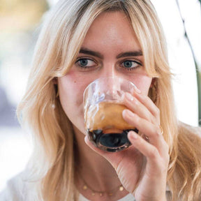 Frau trinkt aus Kaffeeglas GOCCE 220ml, klares Glas mit dunklem Getränk