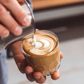 Kaffeeglas GOCCE 220ml wird mit Milchschaum gefüllt, Latte-Art-Motiv sichtbar