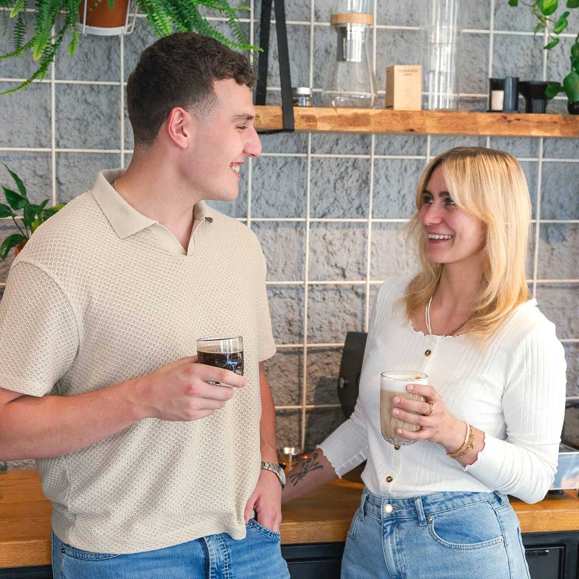 Zwei Personen halten Latte Macchiato Gläser GOCCE in moderner Wohnraum-Umgebung