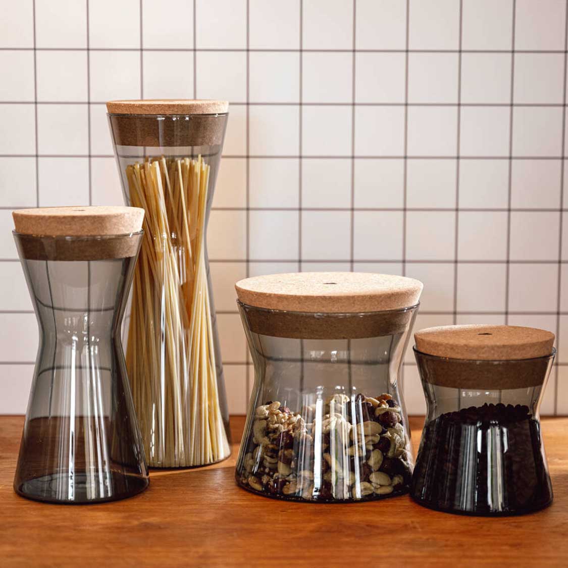 Dose FORMA X mit Korkdeckel neben drei weiteren Behältern mit Füllmaterialien auf Holztisch