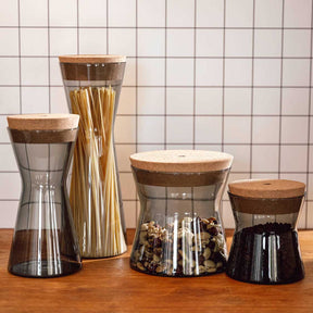 Dose FORMA X mit Korkdeckel neben drei weiteren Behältern mit Füllmaterialien auf Holztisch