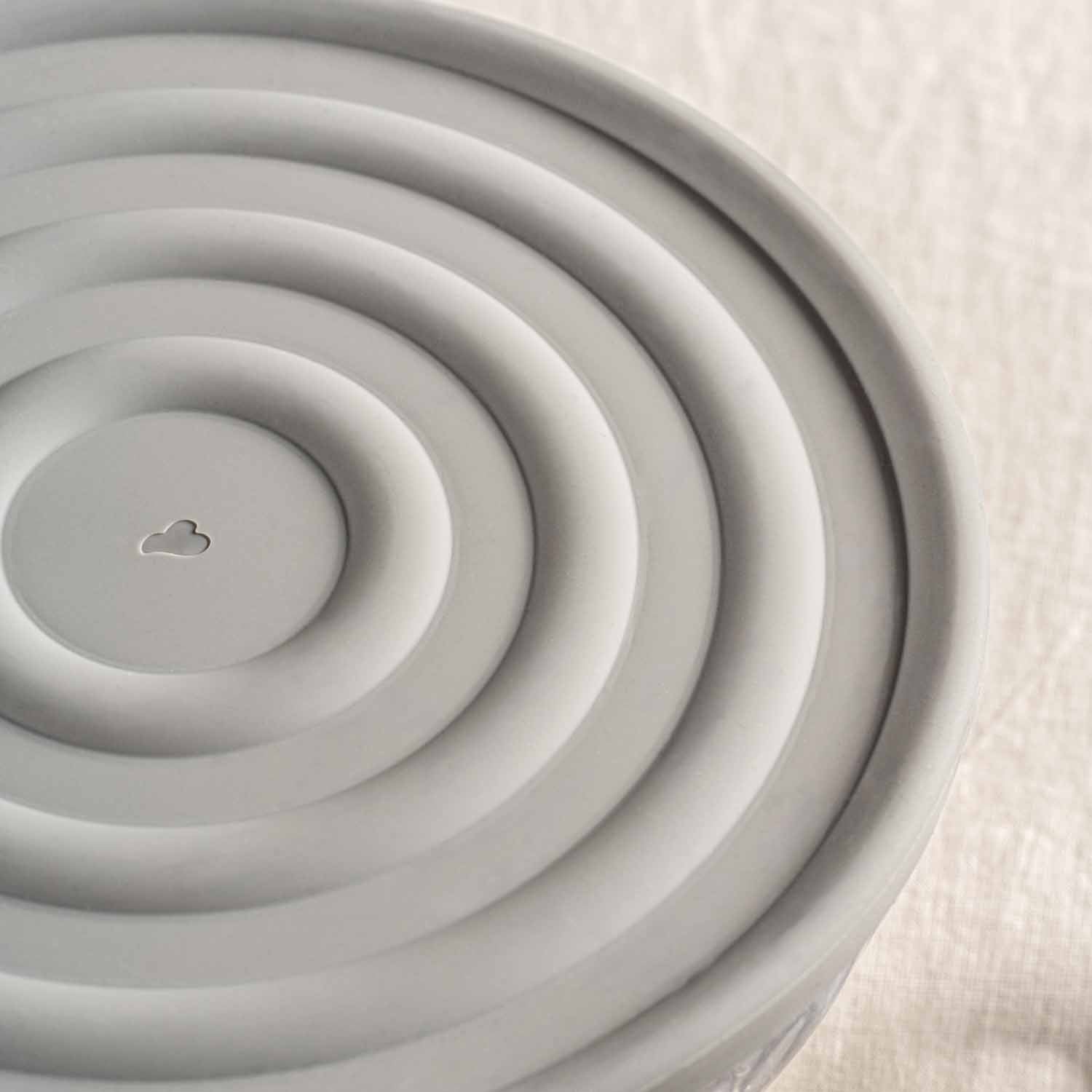 Silikondeckel CUCINA grau von oben, konzentrische Rillen und Wolkensymbol in der Mitte