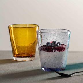 Zwei Trinkgläser mit Getränken, links gelb, rechts transparent mit Beeren