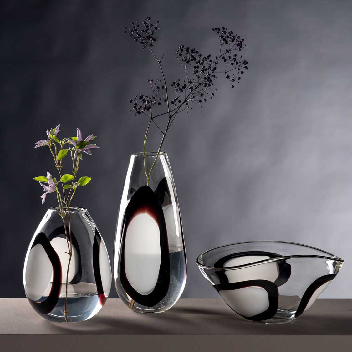 Vase OCCHI BIANCHI mit schwarzen Augen-Motiven, daneben Glasgefäße und getrocknete Blüten