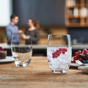Trinkglas CHEERS mit Eiswürfeln und roten Beeren, Küchentresen, zwei Personen im Hintergrund