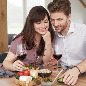 Paar mit Rotweingläsern CIAO+ bei Weinprobe am gedeckten Tisch