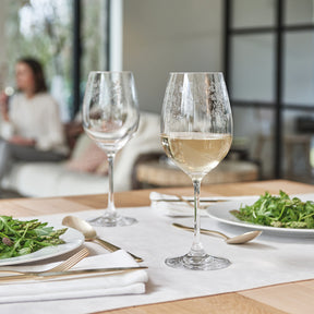 Weißweinglas CHATEAU mit Weißwein gefüllt, gedeckter Tisch mit Tellern und Salat