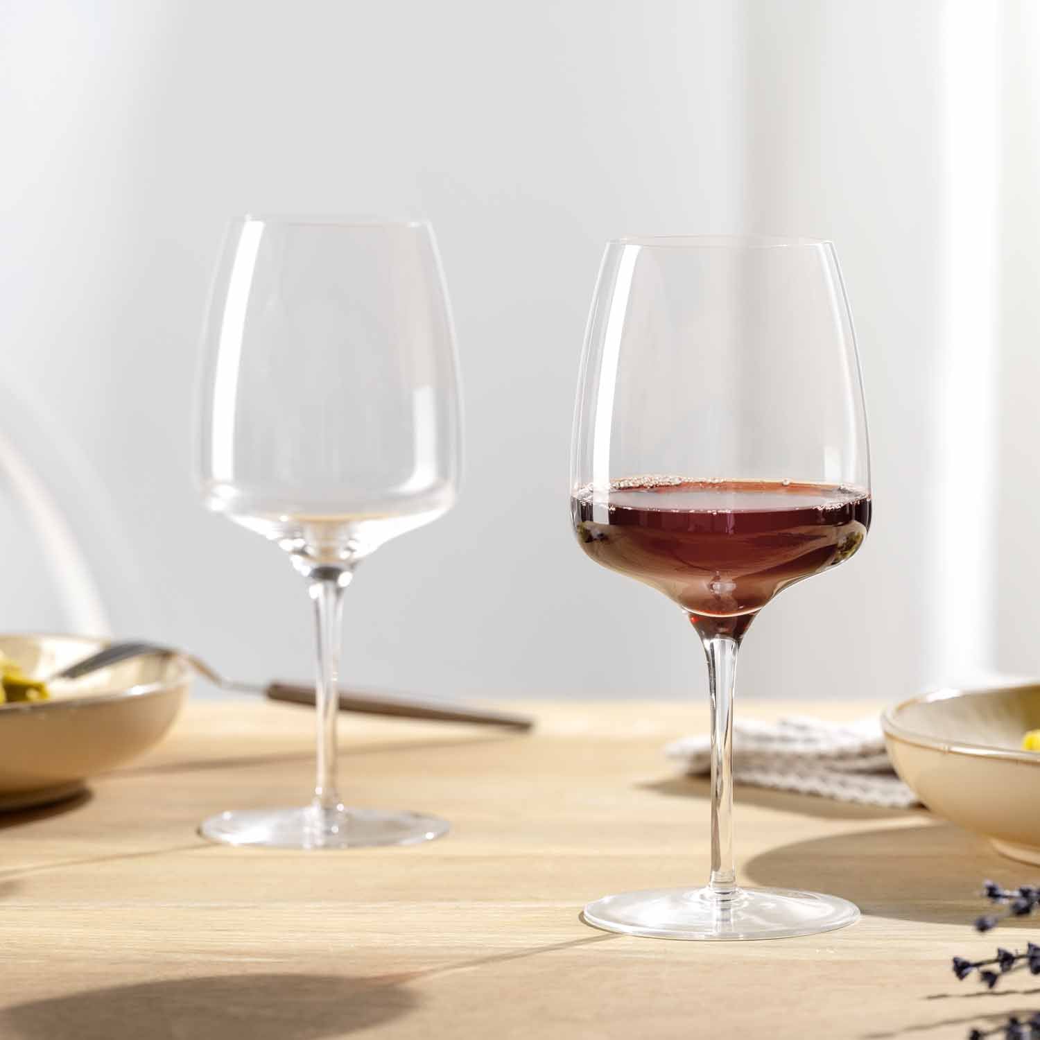 Zwei Rotweingläser CESTI auf gedecktem Tisch, eines leer, eines mit Rotwein gefüllt