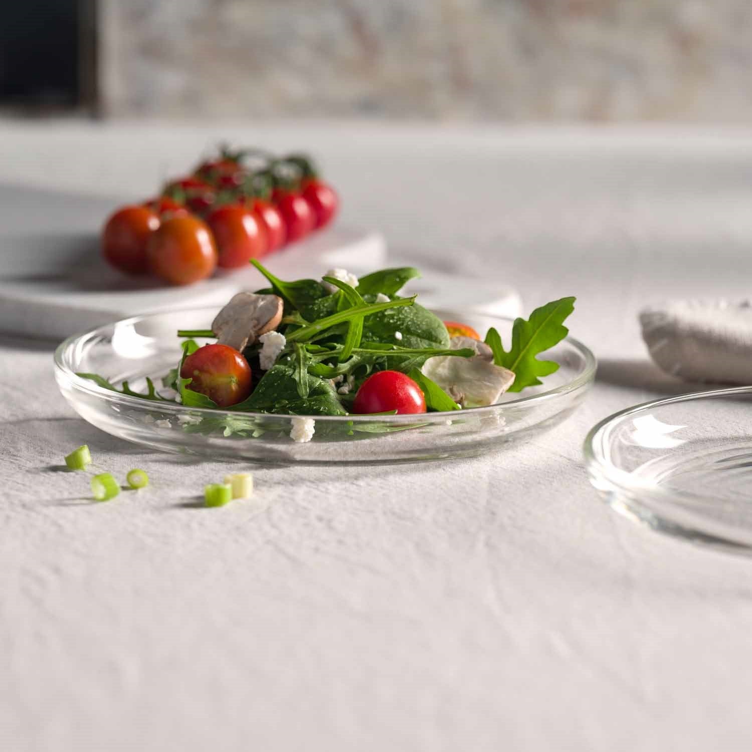 Teller CUCINA mit Salat und Tomaten auf gedecktem Tisch