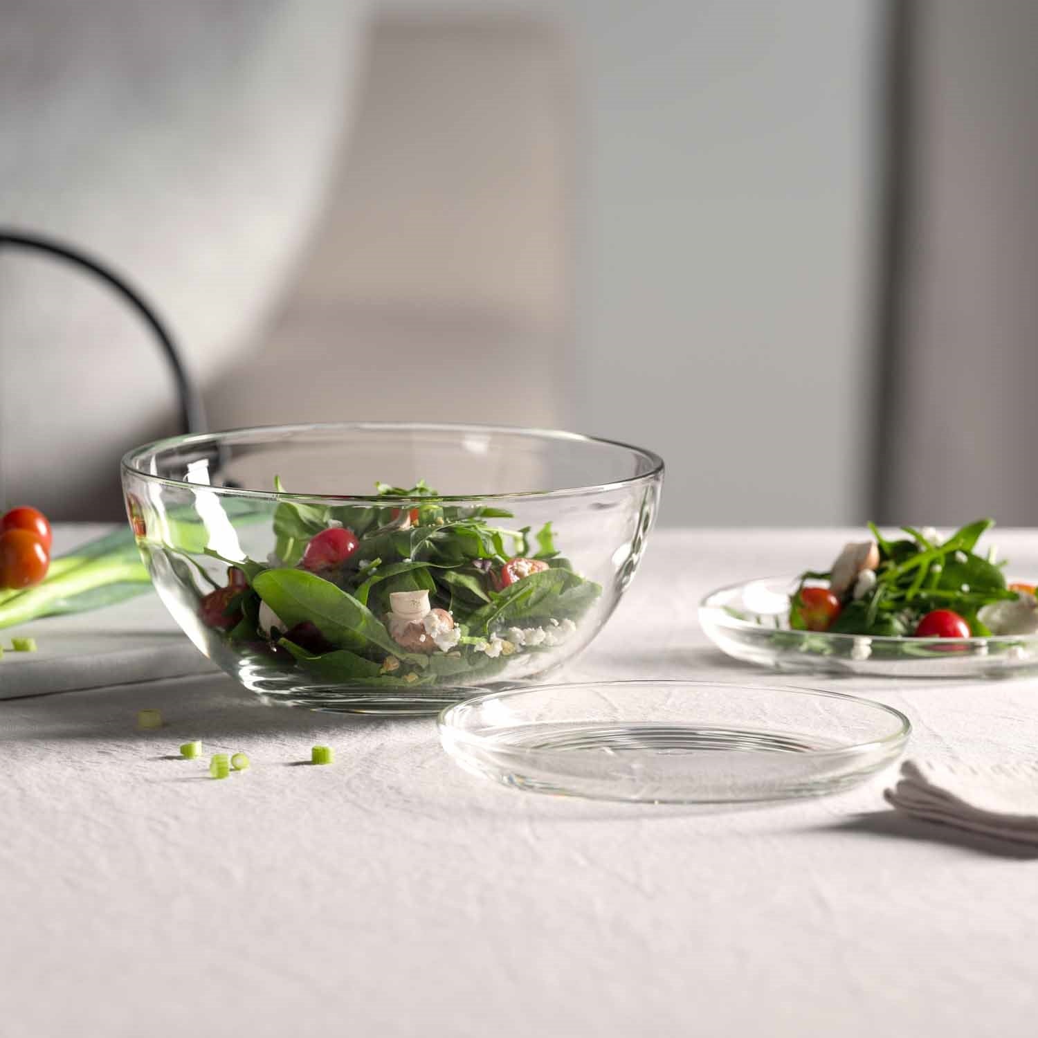 Glasschalen mit Salat auf gedecktem Tisch, Teller daneben