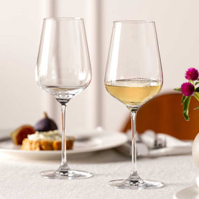 Zwei Rieslinggläser BRUNELLI auf gedecktem Tisch, eines leer, eines mit Weißwein gefüllt