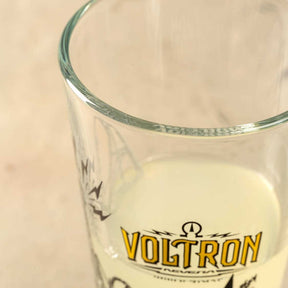 Trinkglas Europa-Park Voltron mit gelbem Logo, teilweise gefüllt mit Flüssigkeit