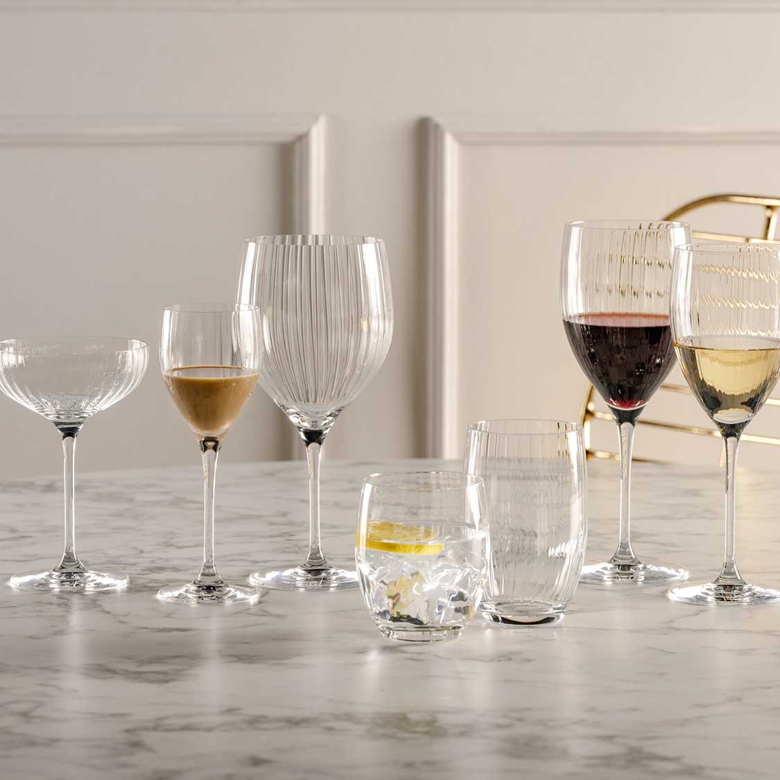 Verschiedene Gläser mit Getränken auf Marmortisch, Cocktailglas POESIA im Set arrangiert