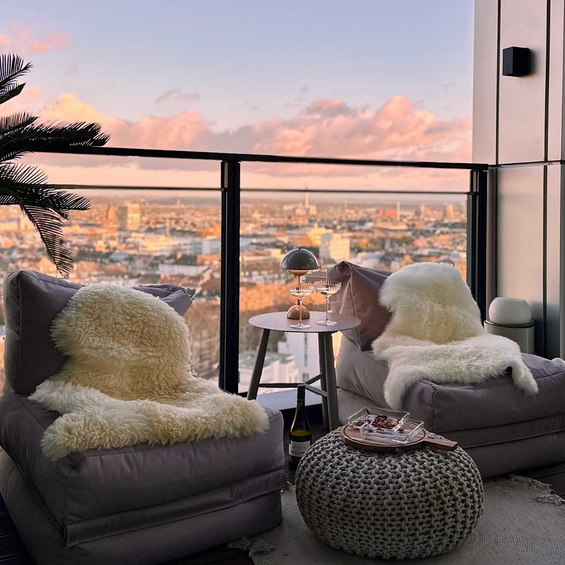Luxuriöser Wohnraum mit Panoramafenster und Stadtblick, Sessel mit Fell-Plaids, Beistelltisch
