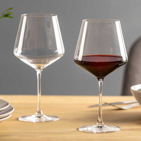 Zwei Burgundergläser PUCCINI mit Wein auf Holztisch, grauer Hintergrund