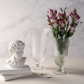 Vase auf Fuß POESIA mit rosa Blüten, neben Büsten und Dekoobjekten auf Marmor