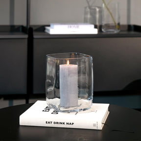 Vase Pietra mit brennender Kerze auf Buch in minimalistischem Wohnraum