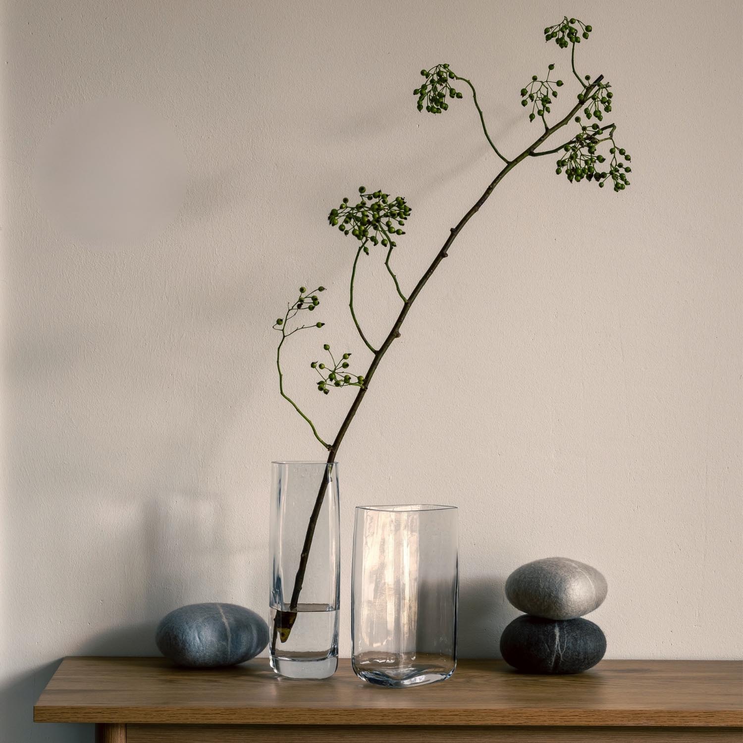 Vase PIETRA mit Grünpflanze auf Holztisch, daneben Steine und Gläser