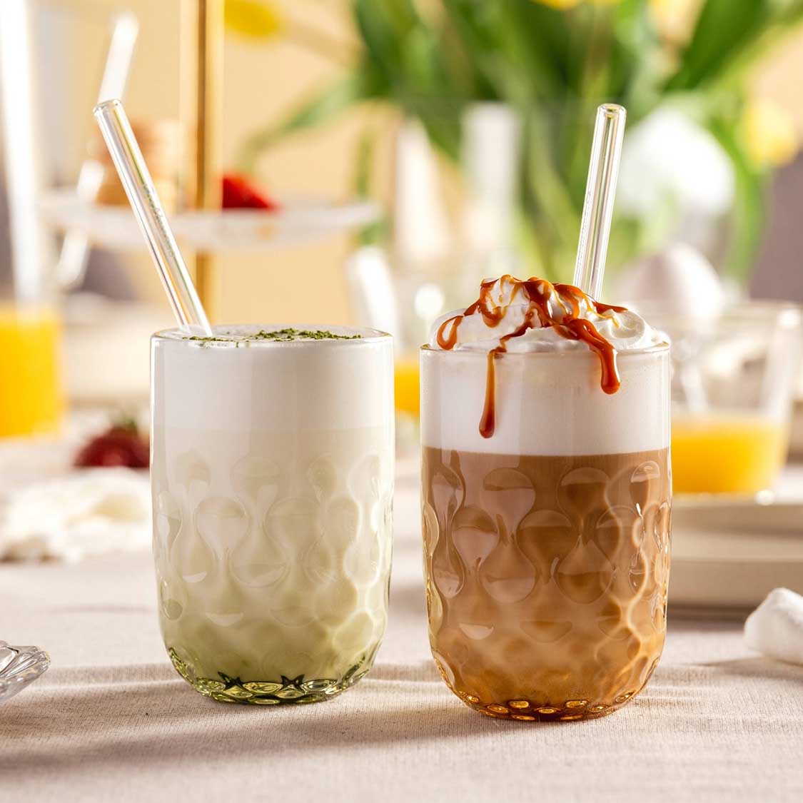Caramel Macchiato Gläser GOCCE mit Glastrinkhalmen auf gedecktem Tisch mit Deko