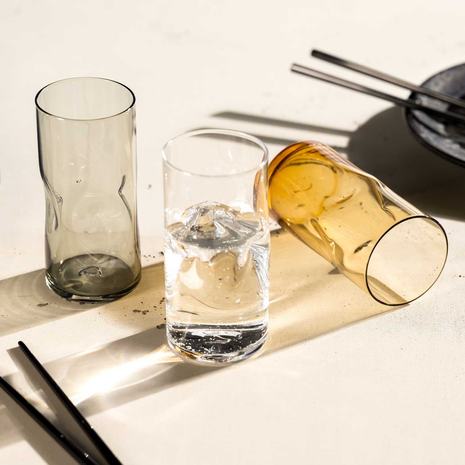 Trinkglas VESUVIO mit Wasser und Zitrone, daneben leere Gläser und Flasche