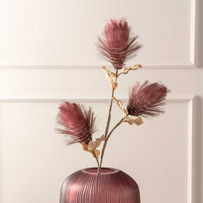 Blütenstamm BELLAGIO mit drei beerenrot gefärbten Blüten in gerippter Vase vor weißer Wand