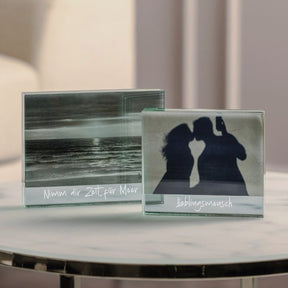 Zwei Glasbilderrahmen LINEA mit Gravur auf Marmortisch, einer mit Meerlandschaft, einer mit Silhouetten von zwei Personen
