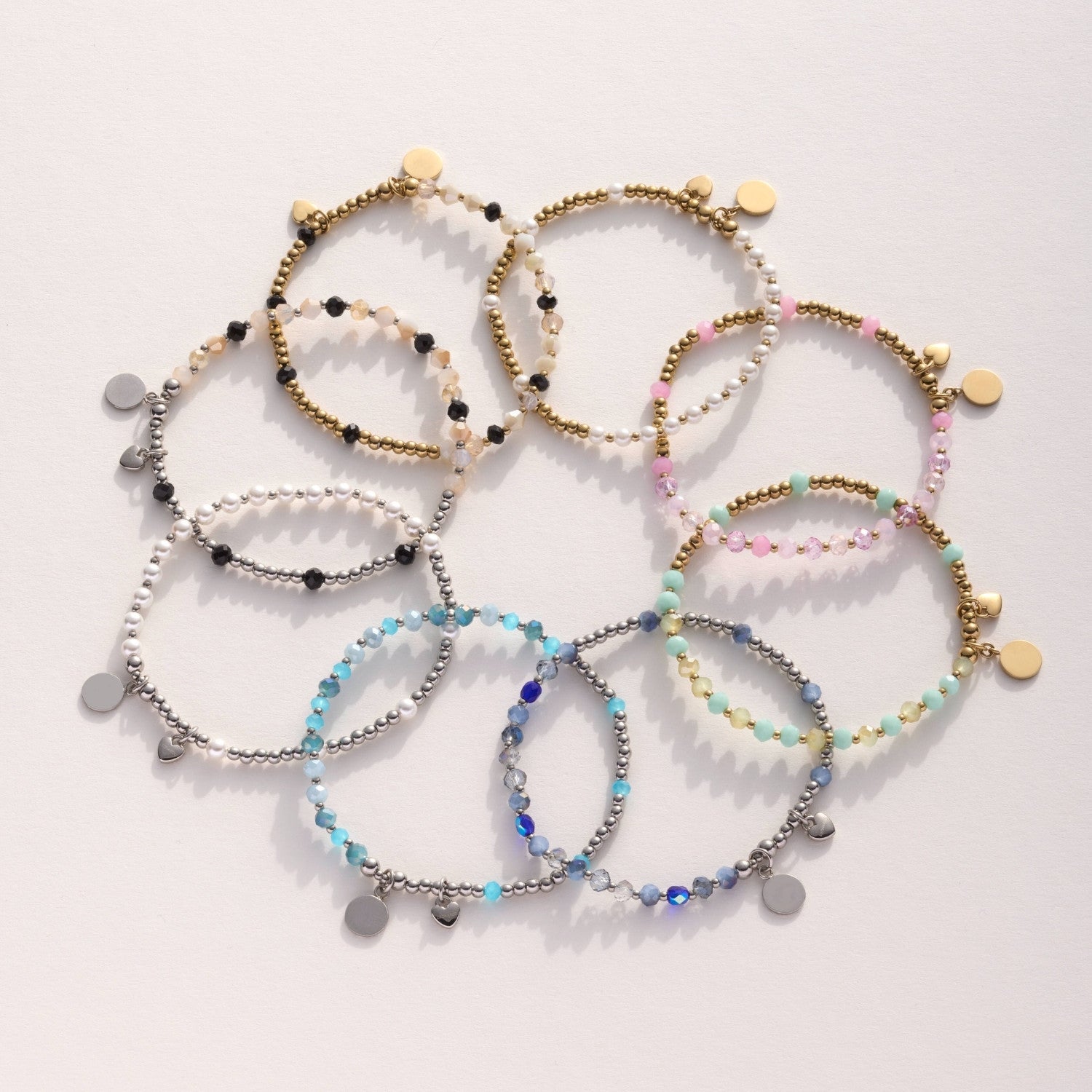 Mehrere Armbänder AMITA You & Me in verschiedenen Farben und mit Metallanhängern auf heller Fläche