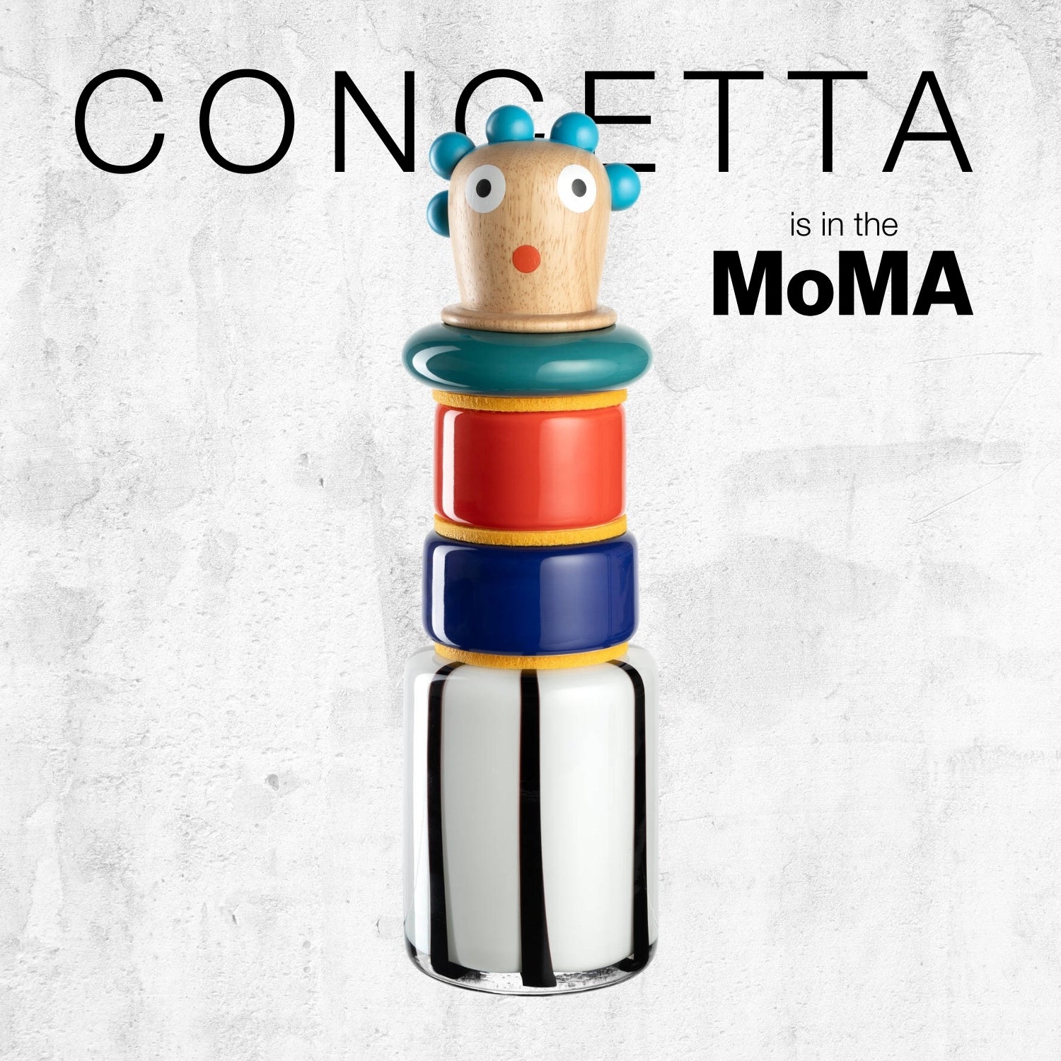 Bunte stapelbare Figur aus Glas und Holz mit blauem Haar, roten und blauen Elementen. Text: „CONCETTA is in the MoMA“.