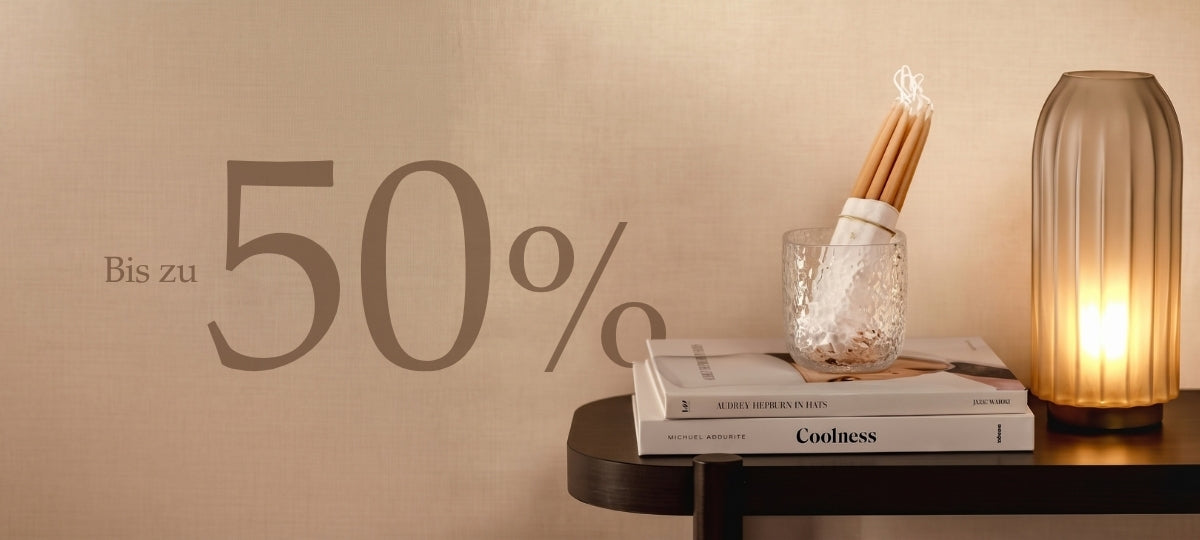Bis zu 50% Rabatt. Herbstliche Dekoration mit Kerze, Buecher und Glas auf dunklem Tisch vor warmbeiger Wand