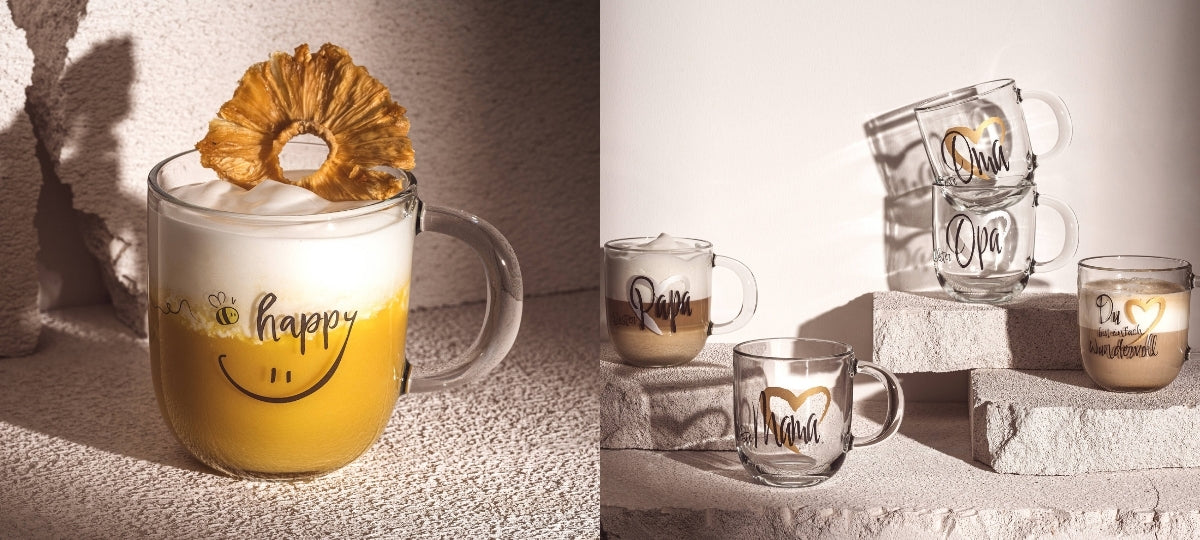 Glastassen und Gläser mit Schriftzügen auf Steinblöcken, warme Beleuchtung, minimalistisches Design