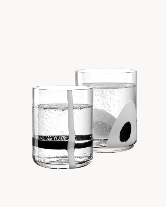 Zwei Trinkgläser mit Wasser und schwarzen Designelementen vor helalem Hintergrund.