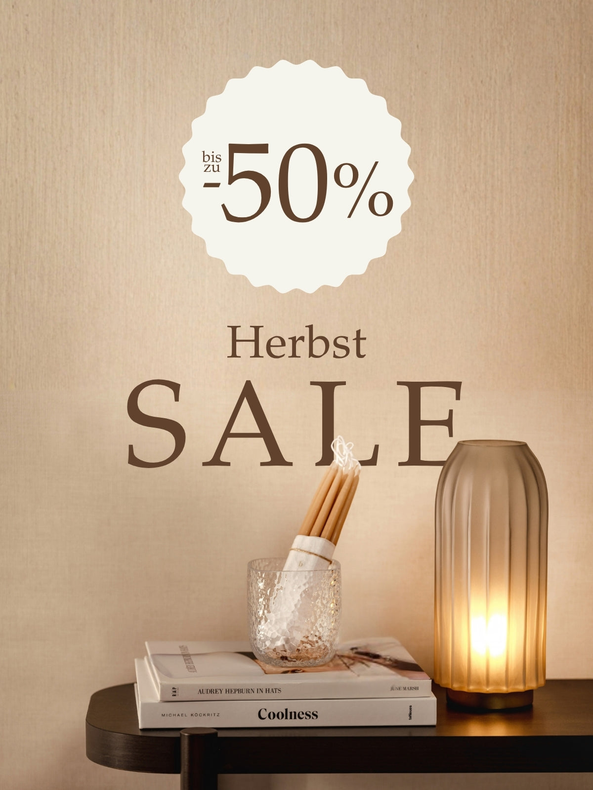 Herbst SALE bis zu -50%, Glasvase mit Kerzen und Büchern auf dunklem Tisch, warme Beleuchtung